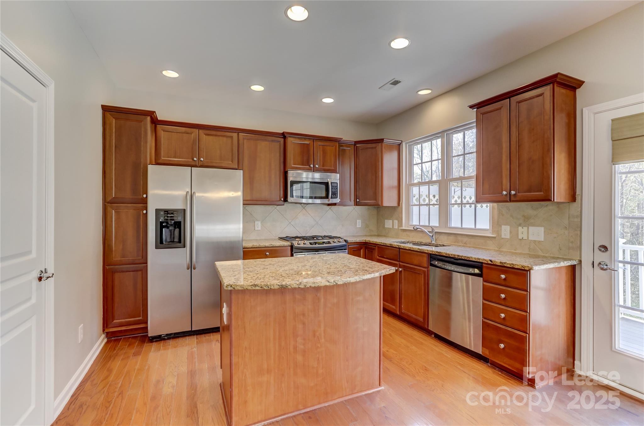 562 6th Baxter Crossing Fort Mill, SC 29708 - Photo 13 of 47 a kitchen with stainless steel appliances granite countertop a refrigerator a sink a stove and wooden cabinets