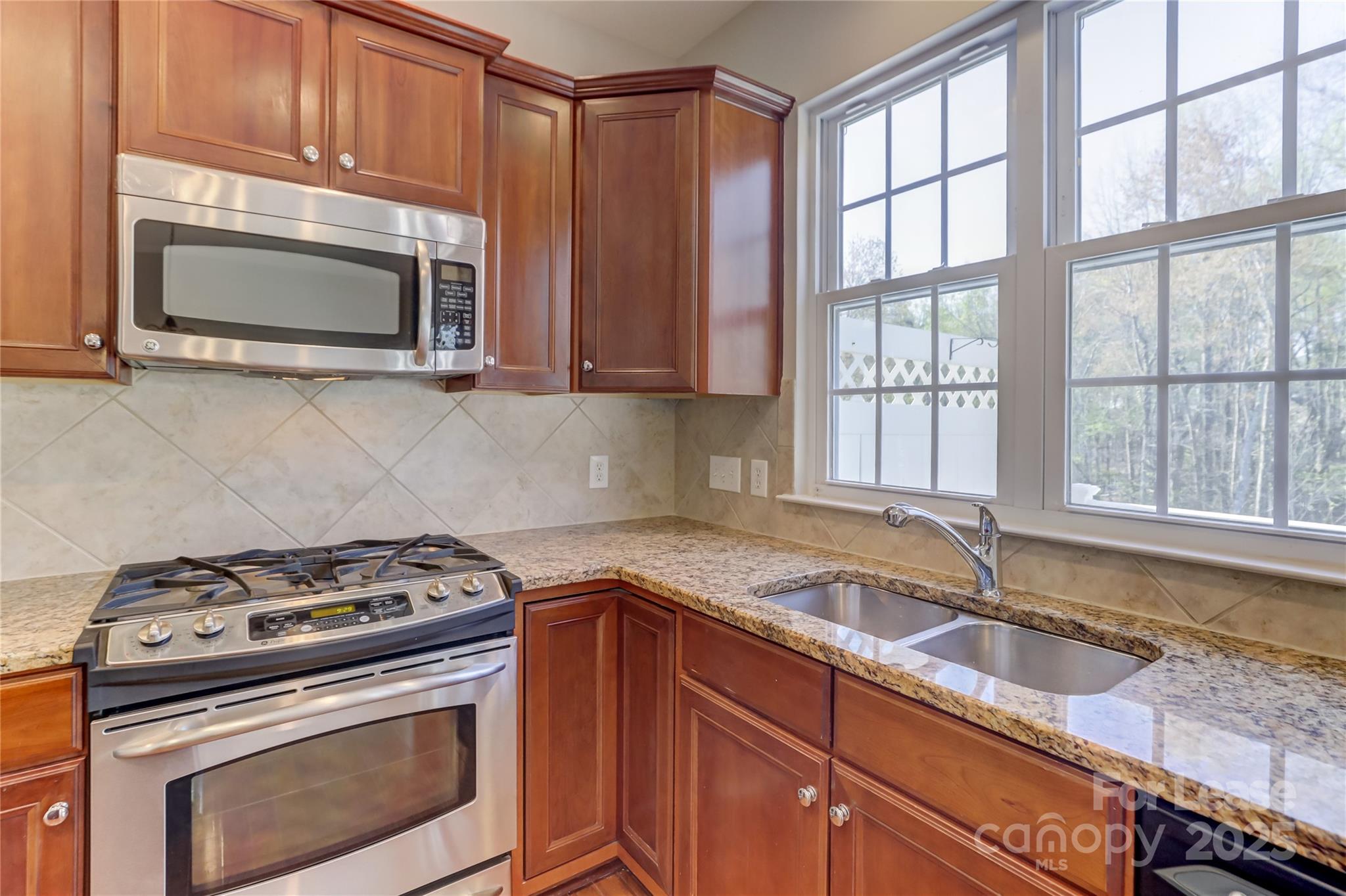 562 6th Baxter Crossing Fort Mill, SC 29708 - Photo 17 of 47 a kitchen with granite countertop a stove a sink and a microwave