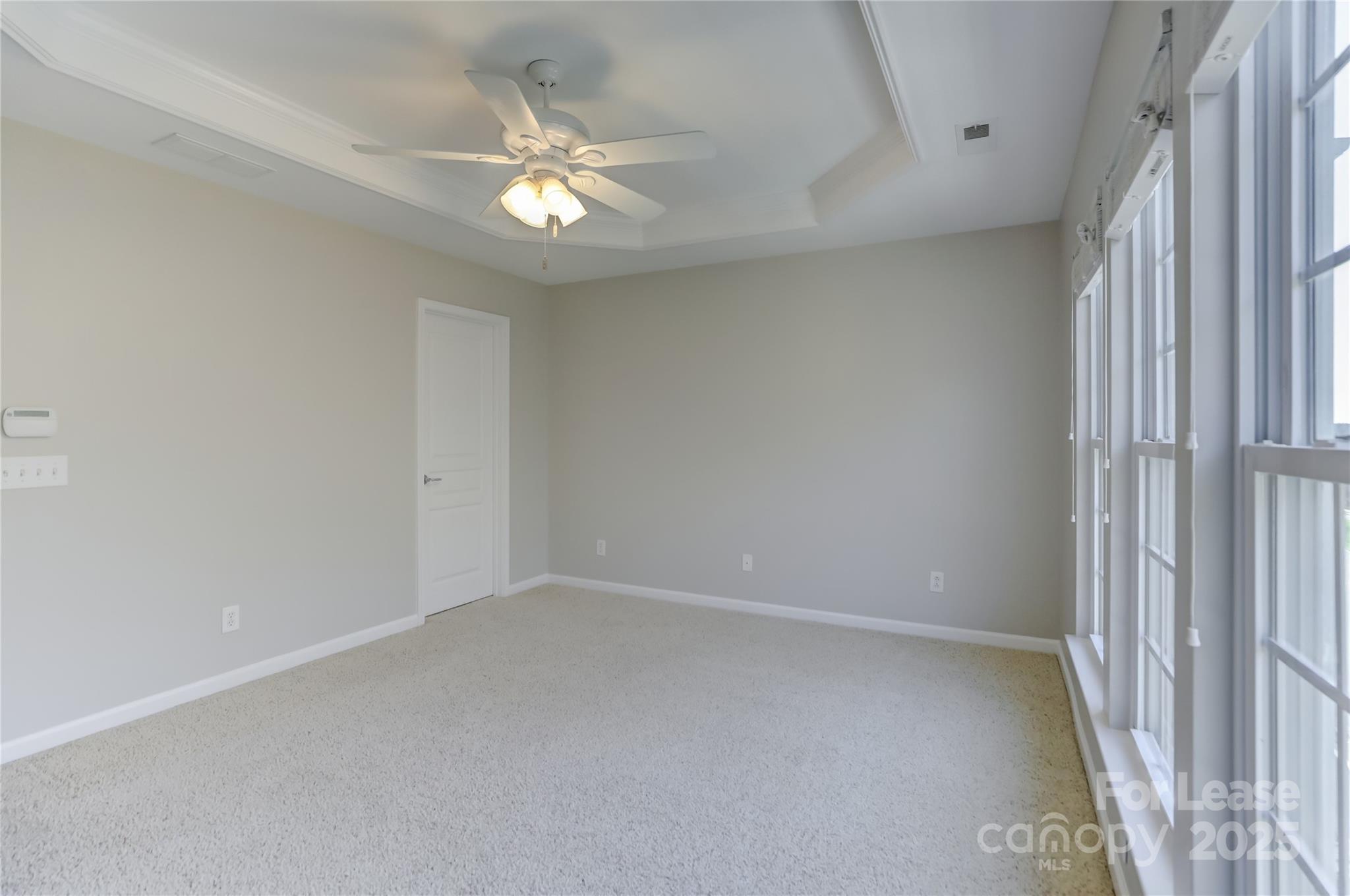 562 6th Baxter Crossing Fort Mill, SC 29708 - Photo 30 of 47 an empty room with a chandelier fan and windows