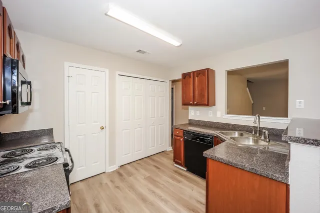 a kitchen with granite countertop a sink stove and cabinets