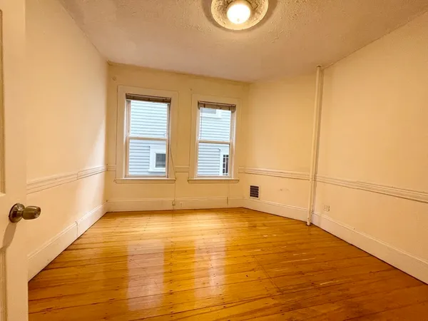 a view of an empty room with a window and wooden floor
