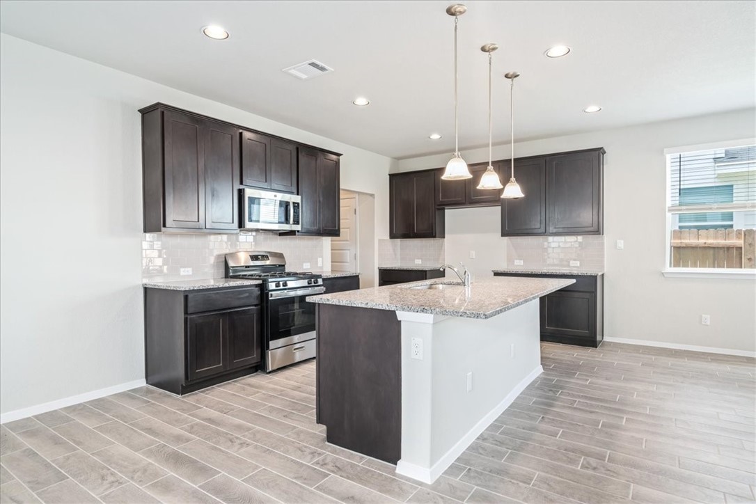 169 Heather Glen Way Maxwell, TX 78656 - Photo 12 of 40 a large kitchen with stainless steel appliances kitchen island granite countertop a stove and a sink
