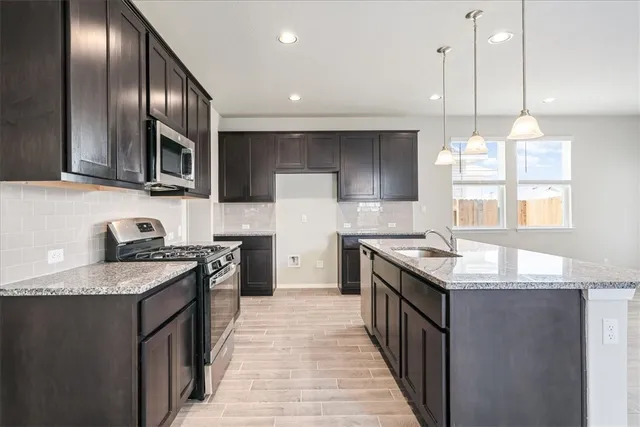 a kitchen with granite countertop stainless steel appliances a sink stove top oven and cabinets