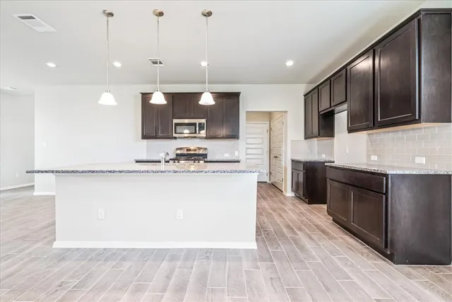 a large kitchen with stainless steel appliances kitchen island granite countertop a stove a sink and a microwave