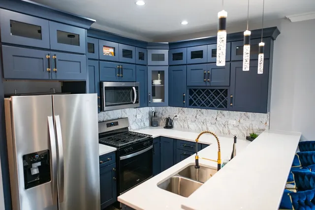 a kitchen with stainless steel appliances granite countertop a refrigerator a stove and a sink with wooden floor