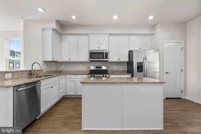 a kitchen with a refrigerator a sink a counter top space and stainless steel appliances