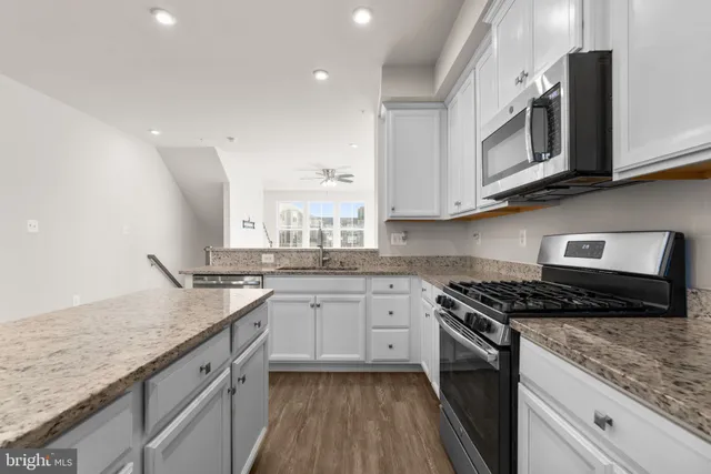 a kitchen with granite countertop white cabinets and white appliances