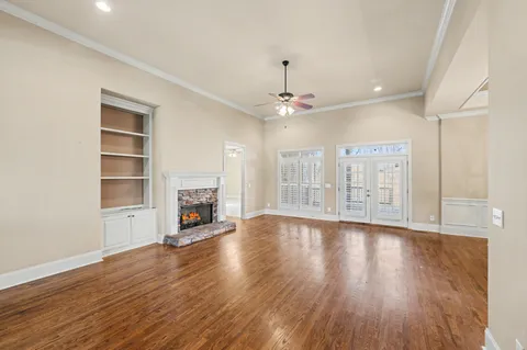 a view of a livingroom with wooden floor a ceiling fan and windows