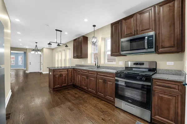 a kitchen with stainless steel appliances kitchen island granite countertop a stove a sink dishwasher and a microwave oven with wooden floor