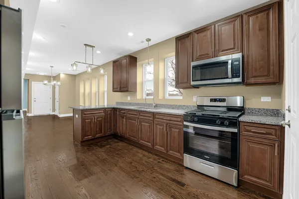 a kitchen with stainless steel appliances granite countertop a stove a sink and a microwave