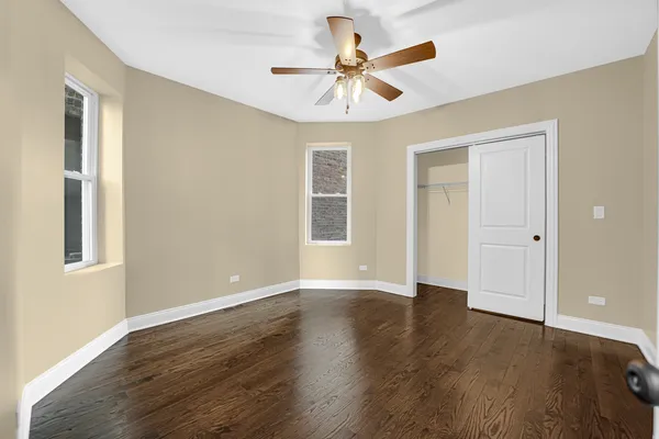 a view of an empty room with window and wooden floor
