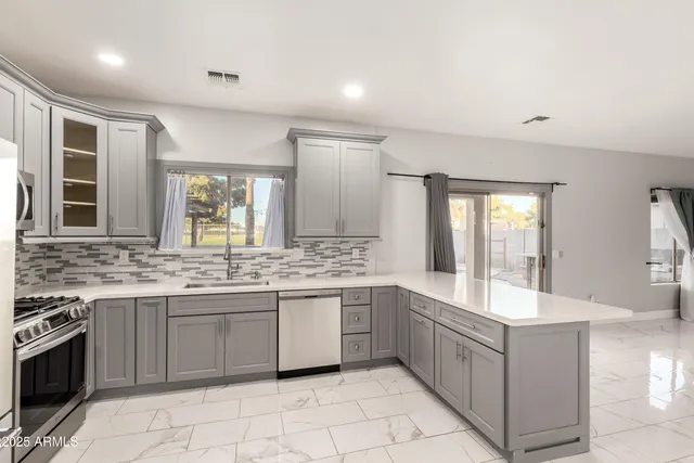 a large white kitchen with a sink and dishwasher a stove with wooden floor