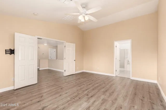an empty room with wooden floor and a ceiling fan