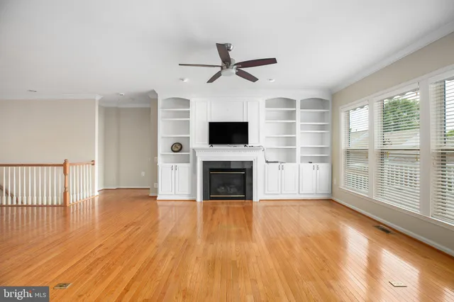a view of a livingroom with a fireplace a ceiling fan and wooden floor