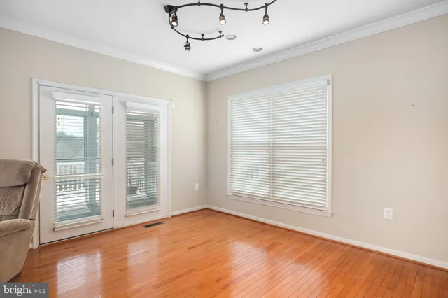 a view of an empty room with a window and wooden floor