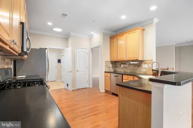 a kitchen with stainless steel appliances granite countertop a sink a stove and a refrigerator