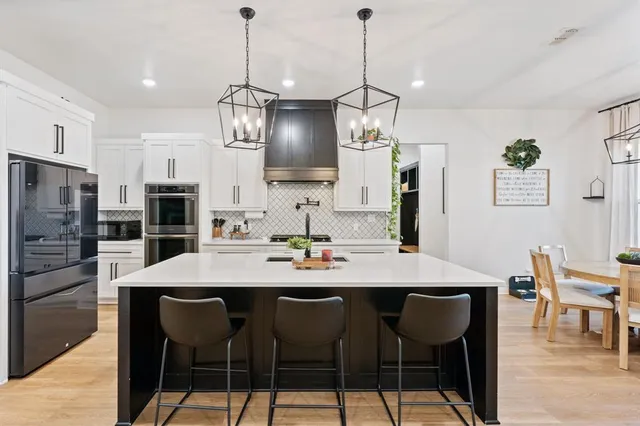 a kitchen with stainless steel appliances a dining table chairs sink refrigerator and stove