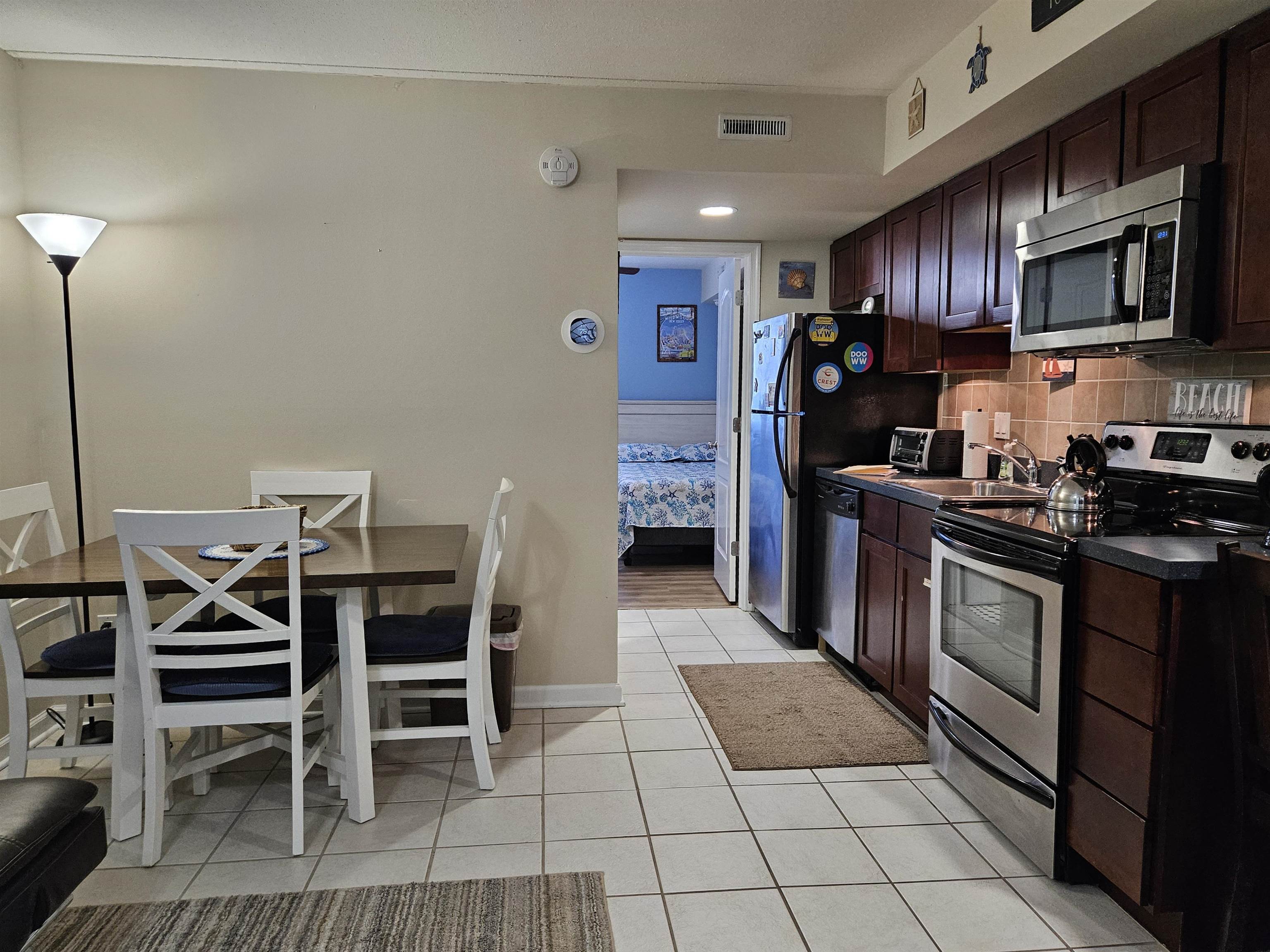 208 East Forget-Me-Not Road, Unit 111 Wildwood Crest, NJ 08260 - Photo 5 of 16 a kitchen with stainless steel appliances granite countertop a stove top oven a sink dishwasher a dining table and chairs