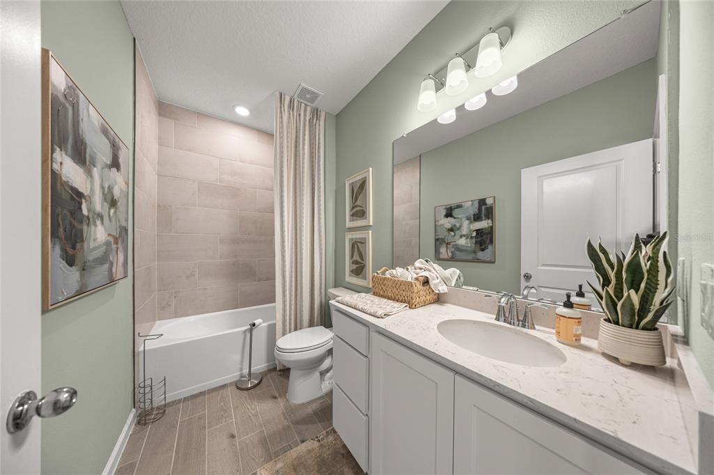 8904 Southwest 69th Terrace Ocala, FL 34476 - Photo 13 of 26 a bathroom with a granite countertop sink a toilet a mirror a bathtub and shower