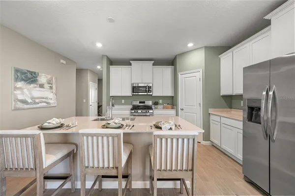 a kitchen with stainless steel appliances granite countertop a dining table chairs refrigerator and microwave