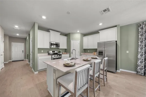 a kitchen with a refrigerator a stove a dining table and chairs