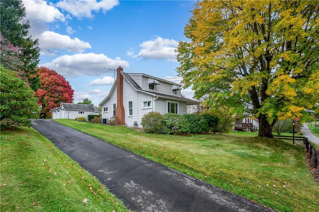 a view of a house with a big yard and large trees