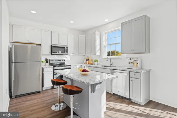 a kitchen with stainless steel appliances granite countertop a refrigerator a sink dishwasher a stove and white countertops with wooden floor
