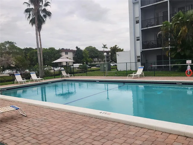 a view of a swimming pool with a yard and palm trees