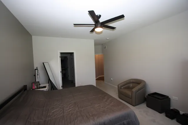 a bedroom with a bed a desk and flowerpot