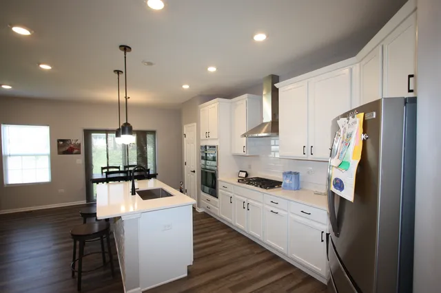 a kitchen with a refrigerator a stove top oven a sink dishwasher and white cabinets with wooden floor