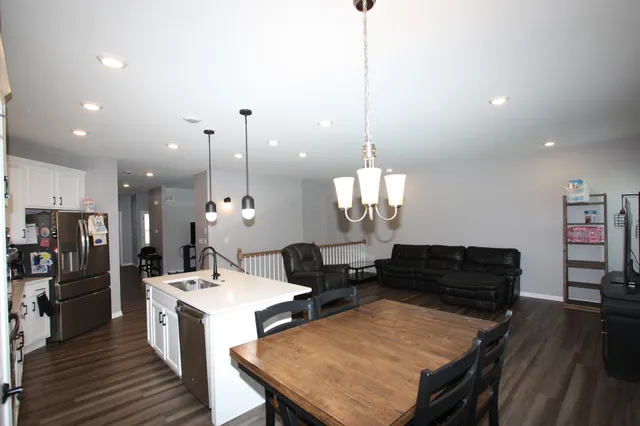 a view of a dining room and livingroom with furniture wooden floor a chandelier