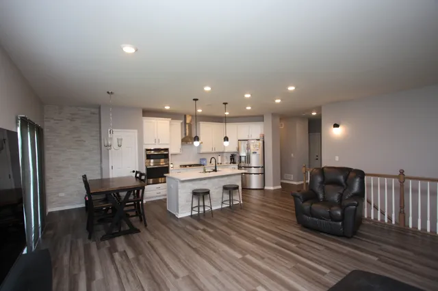 a living room with stainless steel appliances furniture and wooden floor