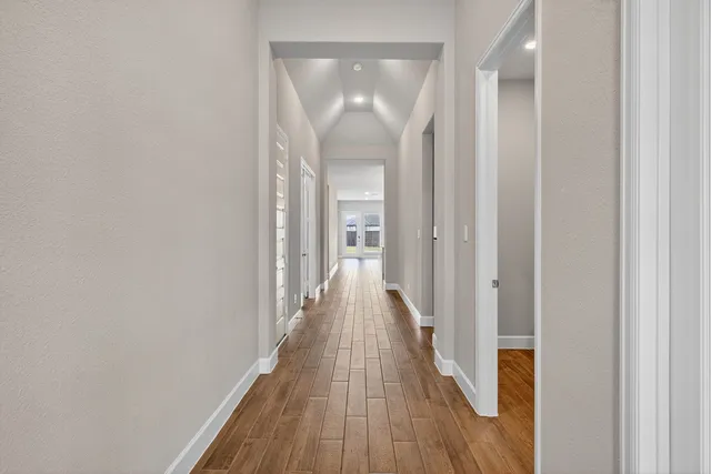 a view of a hallway with wooden floor and a mirror