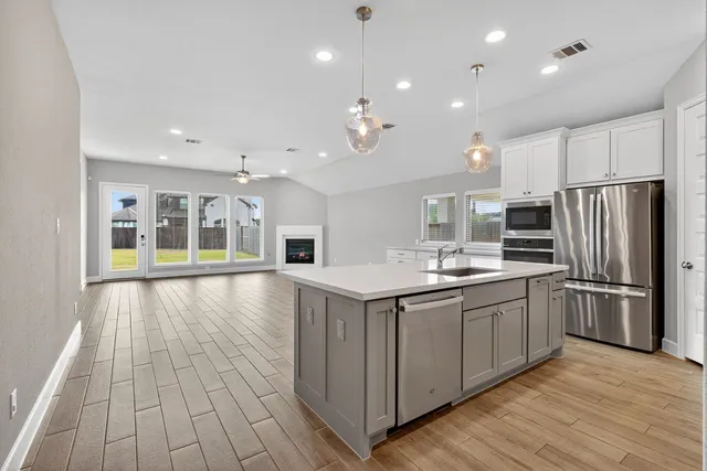 a large kitchen with stainless steel appliances granite countertop a lot of counter space and wooden floors