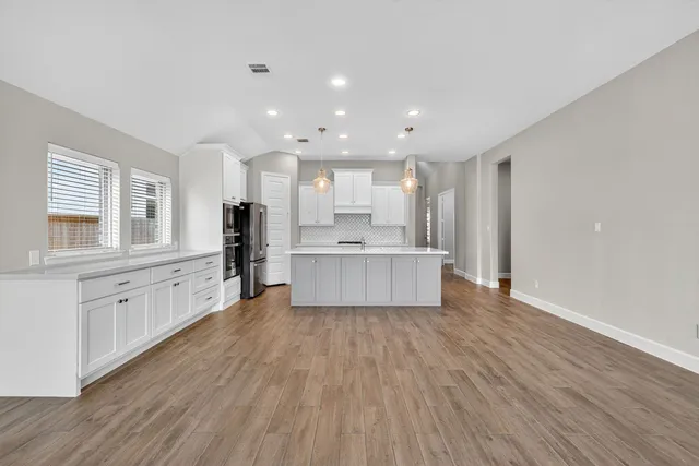 a large kitchen with stainless steel appliances kitchen island a large counter top and a wooden floors