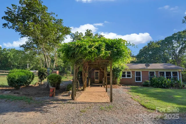 a backyard of a house with table and chairs under an umbrella