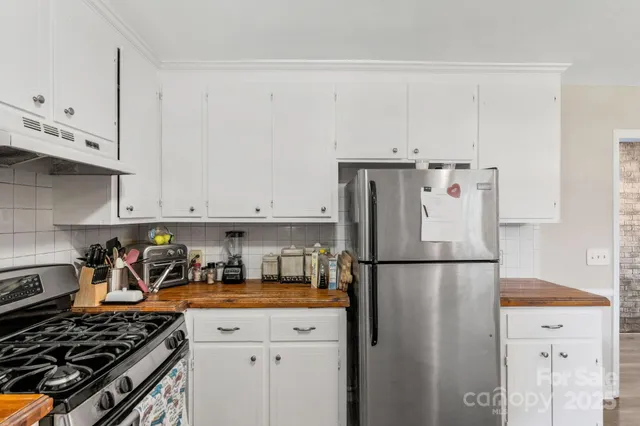 a kitchen with a refrigerator a stove and white cabinets