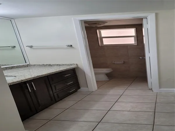 a bathroom with a granite countertop sink a toilet and a mirror