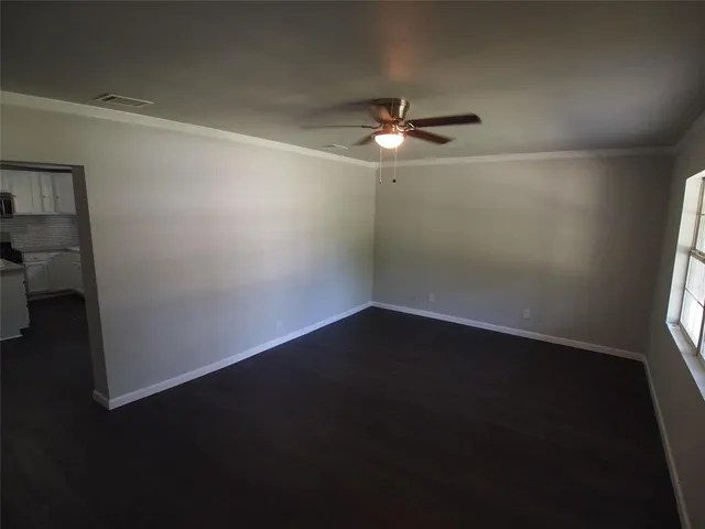 an empty room with wooden floor fan and window