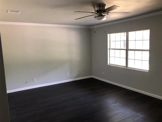 an empty room with wooden floor fan and windows