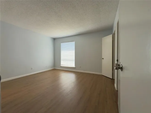 a view of an empty room with wooden floor and closet