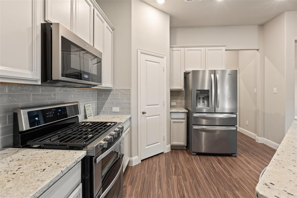 6909 Danridge Road Rowlett, TX 75089 - Photo 8 of 29 a kitchen with granite countertop a refrigerator stove and microwave