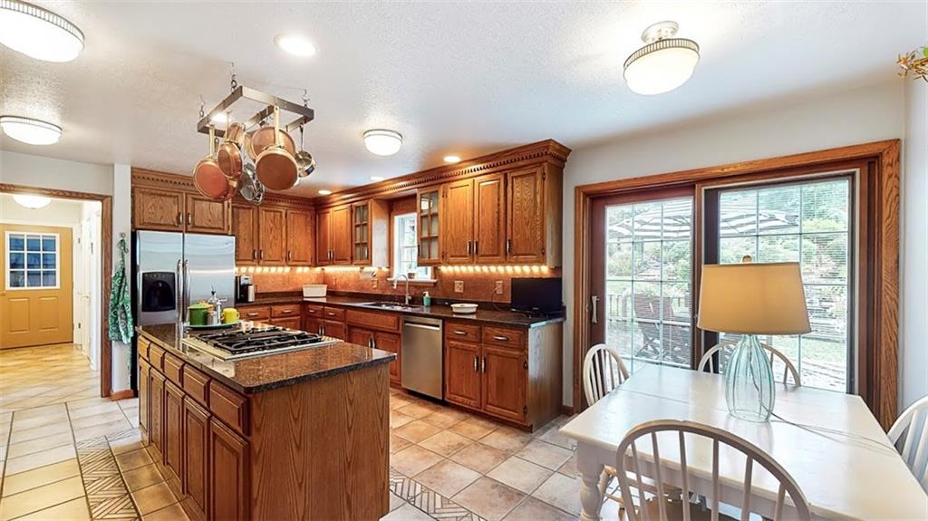 2163 Garards Fort Road Waynesburg, PA 15370 - Photo 11 of 25 a kitchen with stainless steel appliances granite countertop a stove a sink dishwasher a dining table and chairs with wooden floor