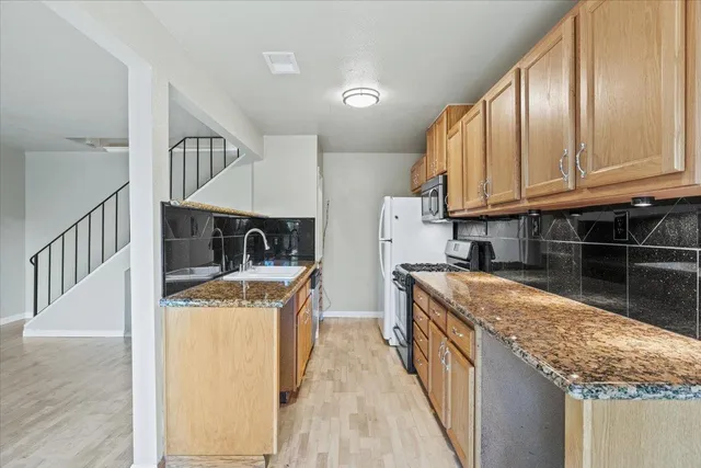 a kitchen with stainless steel appliances granite countertop a stove a sink and a refrigerator