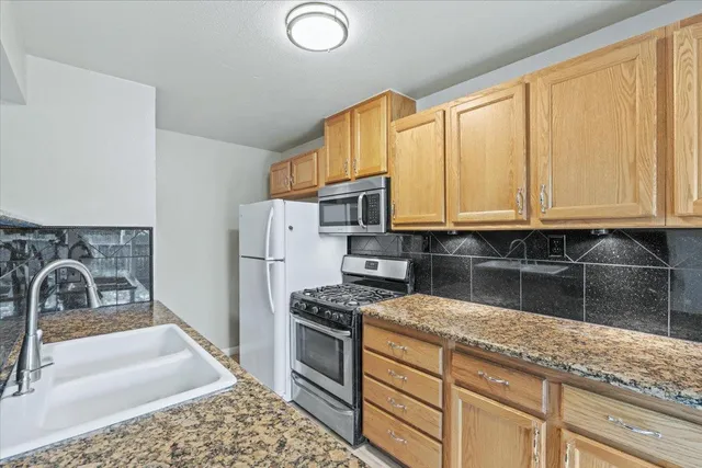 a kitchen with granite countertop a sink cabinets and stainless steel appliances