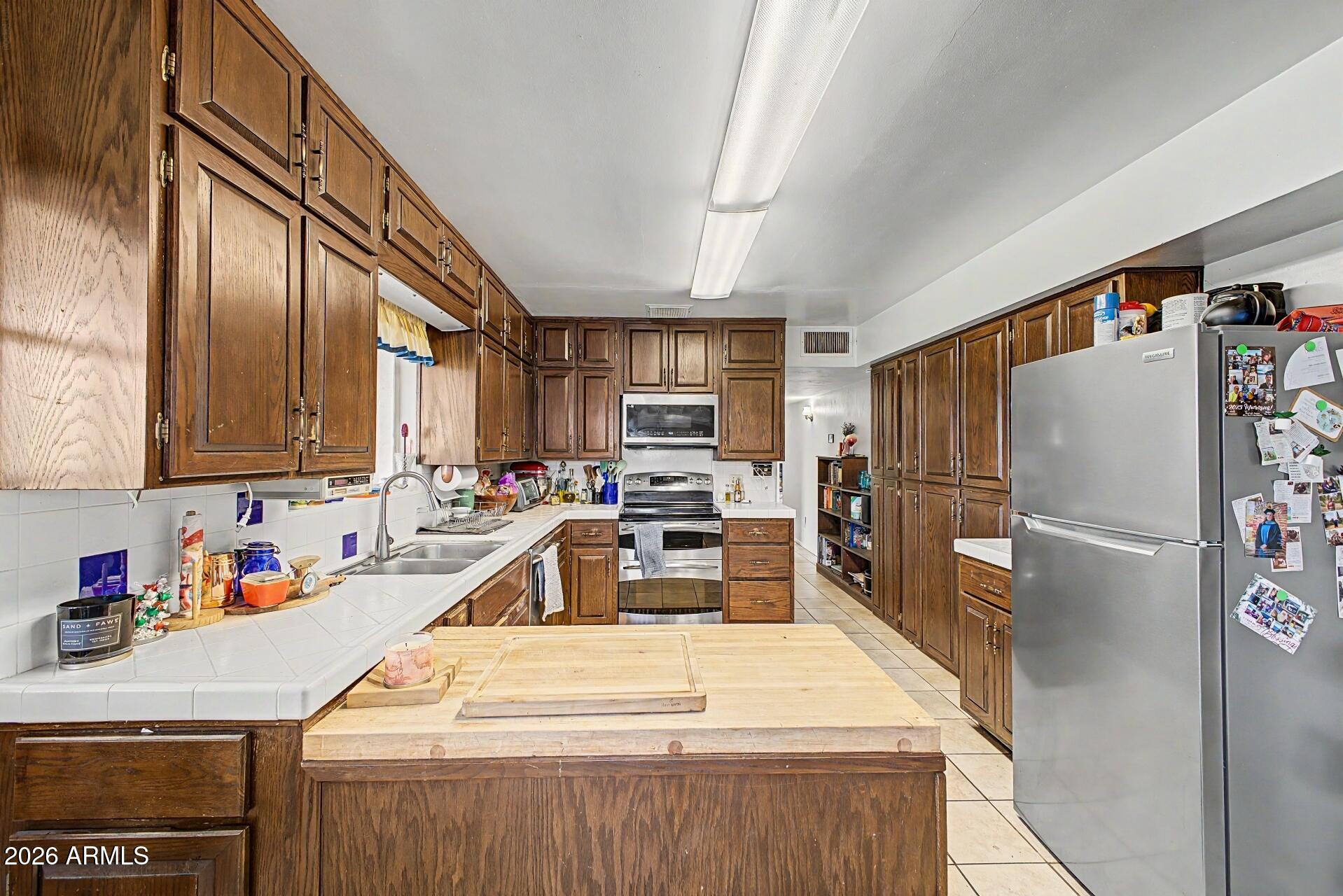 1702 East Griswold Road Phoenix, AZ 85020 - Photo 11 of 38 a kitchen with granite countertop a refrigerator a sink a stove and chairs