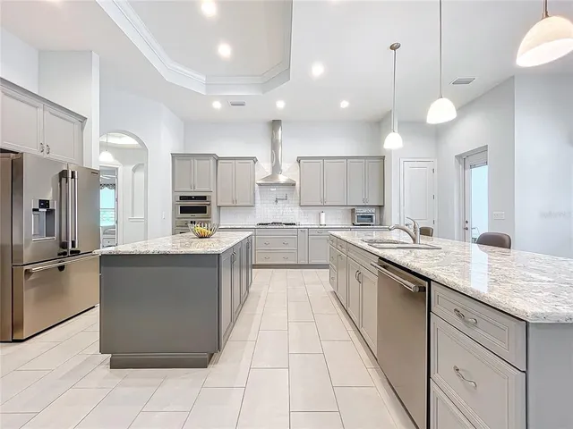 a large kitchen with a large counter top a sink stainless steel appliances and cabinets