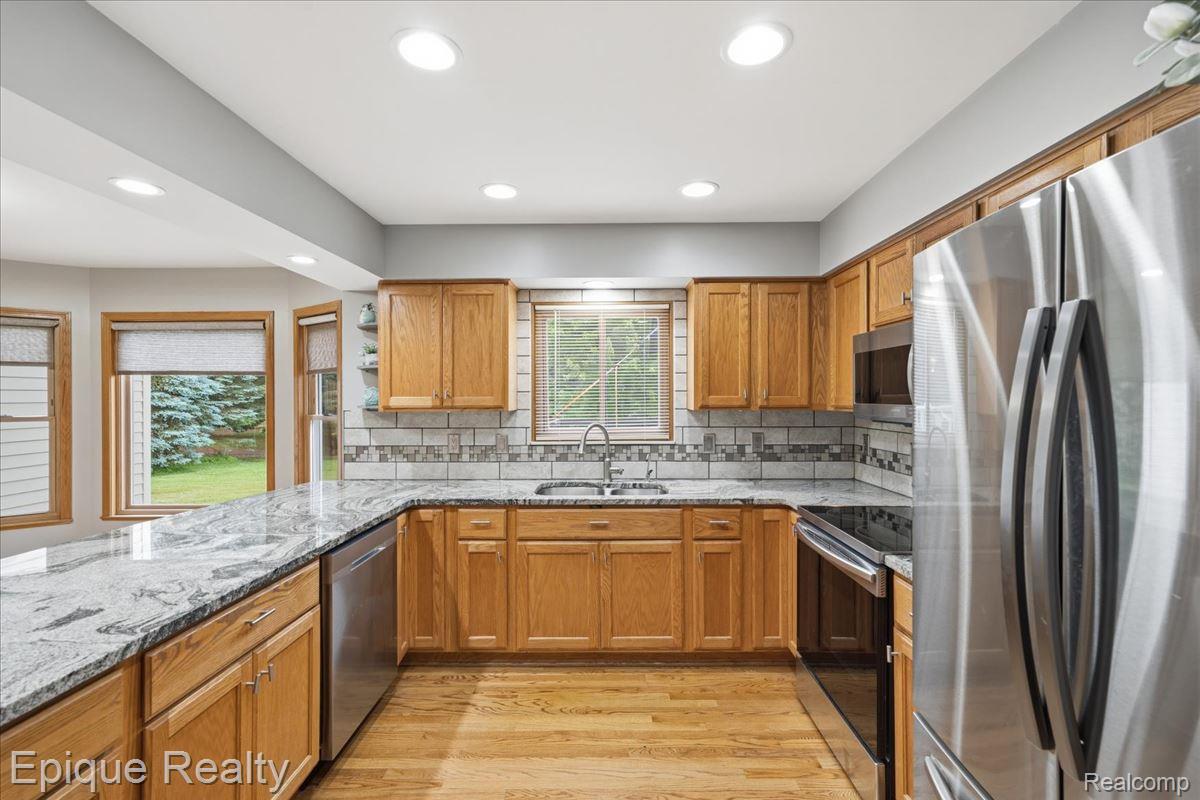 1221 Rhodes Road Lake Orion, MI 48360 - Photo 15 of 72 Kitchen featuring granite countertops, wood-finish flooring, stainless steel appliances, recessed lighting, and light wood cabinetry
