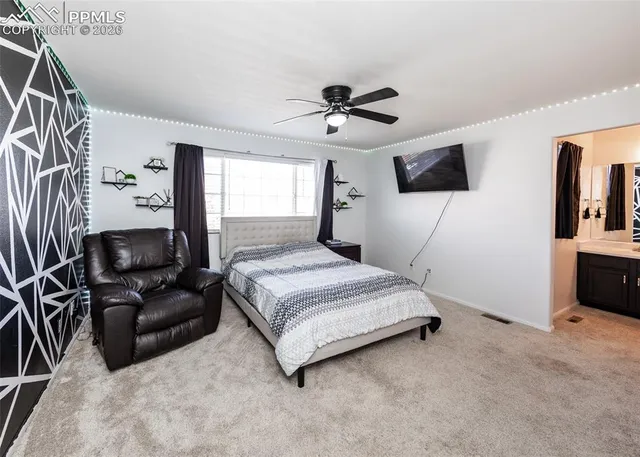 a spacious bedroom with a bed a couch and a flat tv screen on the dresser