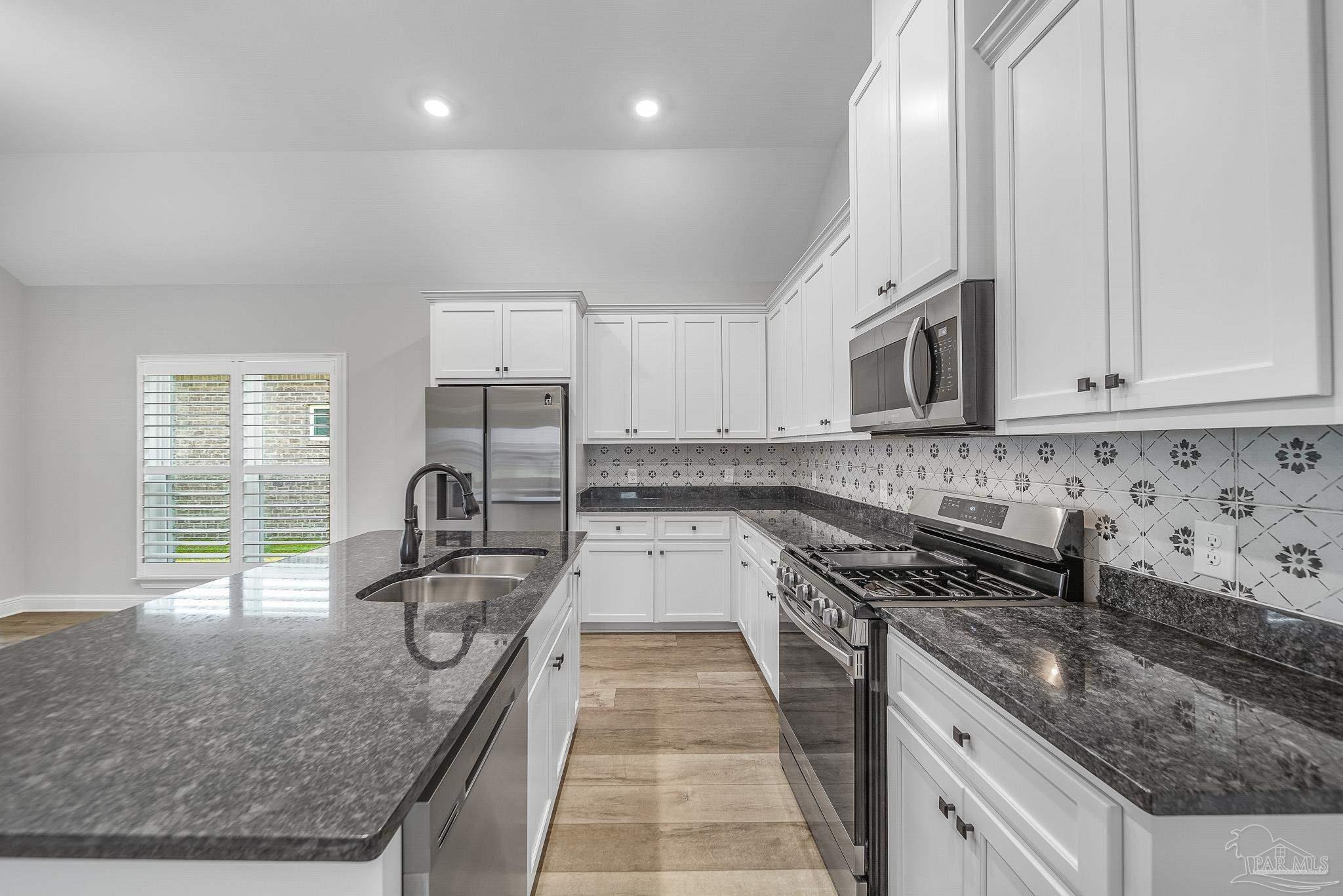8977 Eureka Street Milton, FL 32583 - Photo 7 of 44 a kitchen with granite countertop a sink a counter top space appliances and cabinets